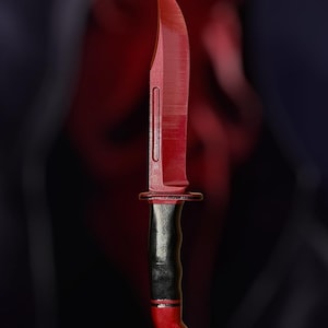 May include: A red and black hunting knife with a black handle and a red blade.