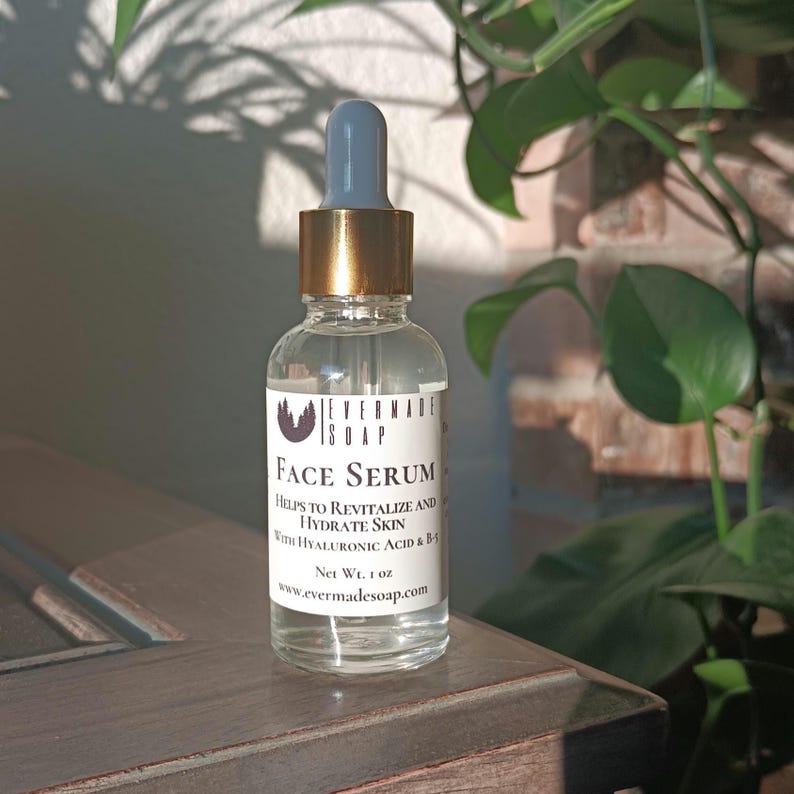 May include: A clear glass bottle of face serum with a blue dropper and gold cap. The label reads "Face Serum" and "Helps to Revitalize and Hydrate Skin." The bottle contains 1 oz of product.