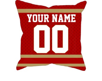 May include: Red and gold throw pillow with a white jersey design. The jersey has the text "YOUR NAME" and the number "00" on it.