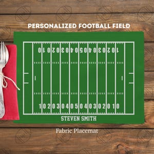Könnte beinhalten: Ein grüner Stoff-Tischset mit einem weißen Footballfeld-Design, einschließlich Yard-Linien und Zahlen. Der Text "PERSONALIZED FOOTBALL FIELD" und "STEVEN SMITH" sind auf dem Tischset aufgedruckt. Eine rote Serviette mit Gabel und Löffel, mit Bindfaden gebunden, befindet sich links.
