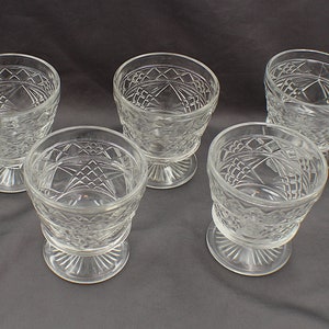 May include: Five clear glass goblets with a cut glass design. The goblets have a round bowl and a short stem with a flared base.