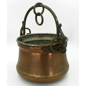 May include: A copper pot with a hammered finish and a wrought iron handle. The pot has a gold trim around the top edge.