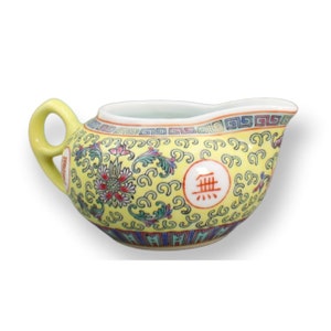 May include: A yellow ceramic teapot with a floral design and a red Chinese character. The teapot has a handle and a spout.