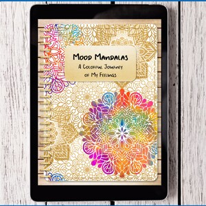 May include: A digital coloring book displayed on a tablet. The cover features the text "MOOD MANDALAS A Colorful Journey of My Feelings" over a gold mandala design. The tablet is on a white wood surface. The bottom of the image reads "JOURNAL MOODS WITH COLOR".