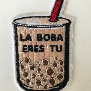 May include: Embroidered iron-on patch featuring a brown boba tea cup with a red straw and the text "LA BOBA ERES TU".