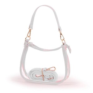 May include: A clear, white, and pink handbag with a shoulder strap and a detachable crossbody strap. The bag has gold-colored hardware and a curved design. The crossbody strap is rolled up and secured with a rubber band.