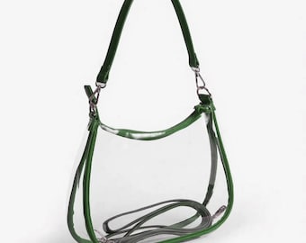 Può includere: Una borsa trasparente con finiture e cinturino verdi. La borsa ha una tracolla e un cinturino più piccolo e staccabile. La borsa è realizzata in materiale trasparente, che consente la visibilità del contenuto. L'hardware è color argento.