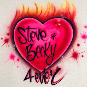 May include: A pink heart with flames on top and the words "Steve & Becky Forever" written in black cursive.