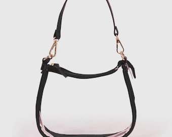 May include: A clear, transparent handbag with a black strap and trim. The bag has a curved shape and a gold-colored clasp. The strap is adjustable and can be worn over the shoulder or carried by hand. The bag is designed to be stylish and functional.