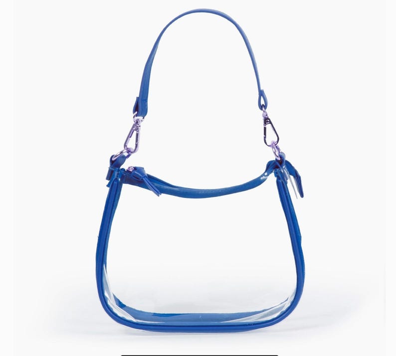 May include: A clear handbag with a bright blue trim, handle, and shoulder strap. The bag has silver-coloured metal clasps and a zip closure. The design is simple and modern, suitable for various occasions.