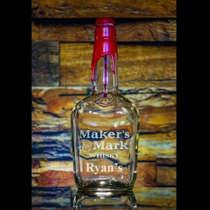 May include: A clear glass bottle with a red wax seal on the top. The bottle is labeled "Maker's Mark Whiskey" and "Ryan's".