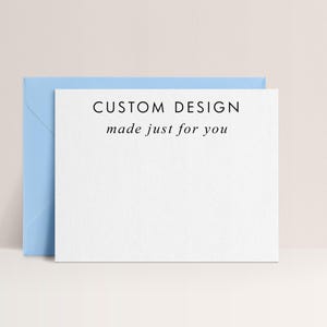 May include: A white card with the text "CUSTOM DESIGN made just for you" is propped up against a light blue envelope. The card and envelope are set against a neutral background.