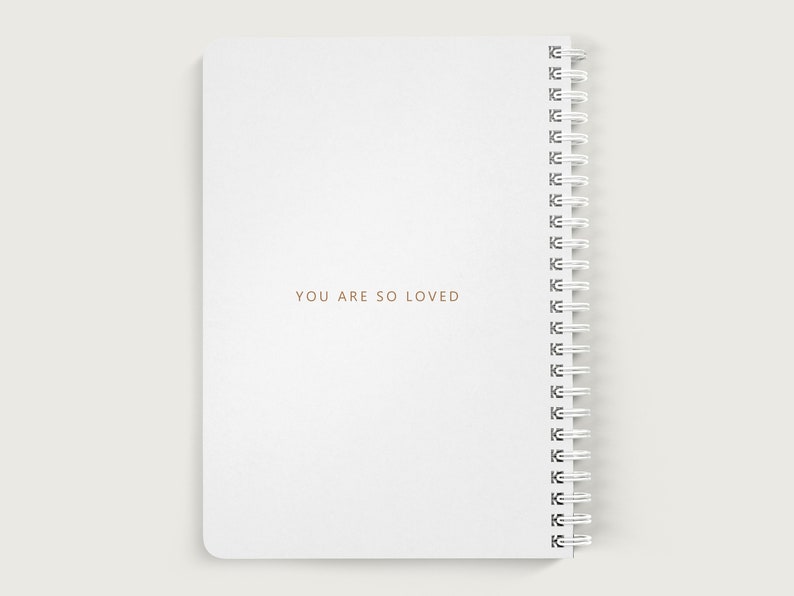 May include: White spiral bound notebook with the text "YOU ARE SO LOVED" printed in gold on the front cover.