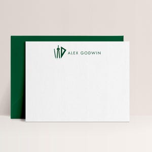 May include: White stationery set with a dark green envelope. The stationery features a dark green logo and the name "ALEX GODWIN" printed in a minimalist style. The set is displayed on a light beige background.