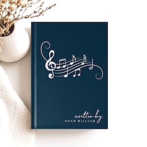 May include: A dark blue notebook with a white musical note design and the text "written by NOAH WILLIAM".