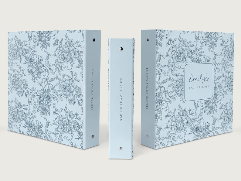 May include: Three light blue binders with a floral pattern. The binders are labeled "Emily's Family Recipes" and feature a square label with the name "Emily's" on the front. The floral design is in a darker blue.