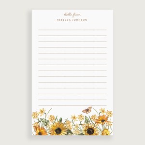 May include: A white notepad with lined paper and a floral design at the bottom. The notepad has the text "hello from" and "REBECCA JOHNSON" printed at the top.