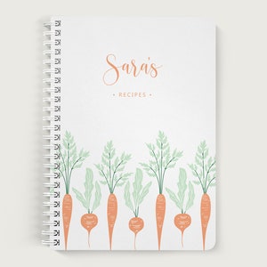 May include: A white spiral bound notebook with the text "Sara's Recipes" on the front cover. The cover has a design of green leafy vegetables and orange carrots.