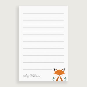 May include: A white lined notepad with a cute fox illustration at the bottom. The notepad has the name "Amy Williams" written at the bottom.