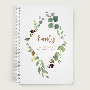 May include: A white spiral bound journal with a green and brown watercolor floral design. The journal has the name "Emily" and the text "Letters to My Daughter" on the front cover.