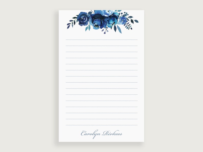Op de afbeelding: Notitieboekje met gestreept papier en een blauw bloemenmotief. Onderaan staat de naam "Carolyn Rivkees" gedrukt.