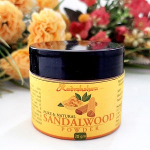 May include: A small, round jar of sandalwood powder with a black lid. The jar is labeled "Pure & Natural Sandalwood Powder 20 gm" and features a small image of sandalwood sticks and leaves.