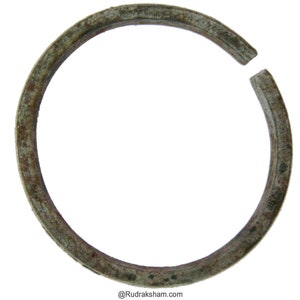 Puede incluir: Un anillo de metal oxidado con un espacio. El anillo es circular y tiene una superficie rugosa y texturizada.