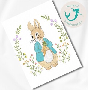 Può includere: Ricamo di un coniglio marrone che tiene una carota, circondato da fiori verdi e viola. Il disegno è su sfondo bianco e include il testo "Mermaid Embroidery".