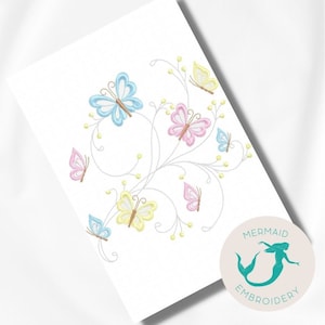 Pode incluir: Desenho bordado com um ramo floral com várias borboletas em tons de azul, rosa e amarelo. O desenho é rodeado por um fundo branco e um logotipo circular com o texto "Mermaid Embroidery".