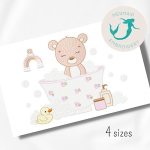 以下が含まれることがあります： ピンクと白の浴槽にピンクの花が咲いている中で、茶色のぬいぐるみが風呂に入っている刺繍のデザイン。浴槽の上には黄色いアヒルと虹があります。デザインには「4サイズ」というテキストが含まれています。