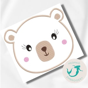 Pode incluir: Desenho bordado de um rosto de urso branco com nariz e olhos castanhos, bochechas cor-de-rosa e cílios. O desenho está sobre um fundo branco.