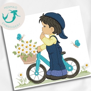 Puede incluir: Diseño bordado de un niño montando una bicicleta azul con una cesta de flores blancas. El niño lleva una gorra azul, una camisa amarilla y un mono azul. Hay mariposas volando alrededor del niño.