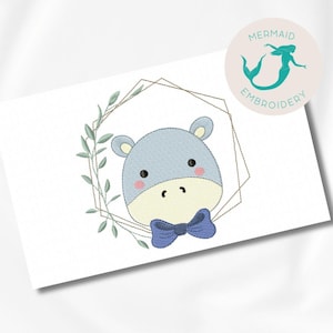 Peut inclure: Broderie représentant un hippopotame bleu portant un nœud papillon bleu, entouré d'un cadre géométrique doré et de feuilles vertes.