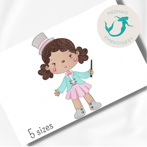 Pode incluir: Desenho bordado de uma menina vestida de maga, com um chapéu-coco, uma jaqueta azul, uma saia rosa e segurando uma varinha mágica. O desenho é de estilo cartoon com cabelo castanho, olhos castanhos e bochechas rosadas.