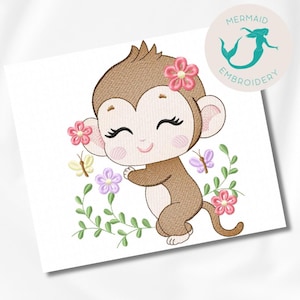 Pode incluir: Desenho bordado de um macaco marrom com flores rosa e borboletas. O macaco está sorrindo e tem os olhos fechados. O design é perfeito para um quarto de bebê ou um quarto de criança.