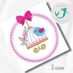 May include: A pink and white birdcage with a blue bird inside, hanging from a pink bow. The cage is surrounded by a pink scalloped circle with the text "Mermaid Embroidery" in a circle above.