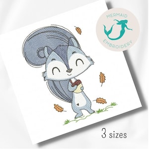 May include: Embroidered design of a cute cartoon squirrel holding an acorn. The squirrel is blue and grey with a big bushy tail. The design is surrounded by falling leaves in shades of orange and brown.