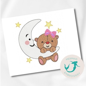 Pode incluir: Desenho bordado de um urso de peluche castanho com um laço rosa, aninhado numa lua crescente branca com uma cara sorridente. O desenho é rodeado por estrelas amarelas.