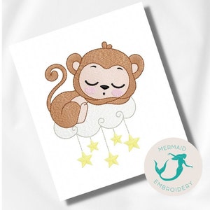 Pode incluir: Desenho bordado de um macaco castanho dormindo em uma nuvem branca com estrelas amarelas penduradas nela. O desenho é rodeado por um fundo branco.