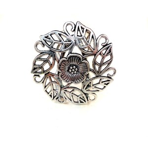 Pu&ograve; includere: Anello floreale in argento con un design delicato che presenta un fiore con un centro di piccoli punti circondati da foglie.