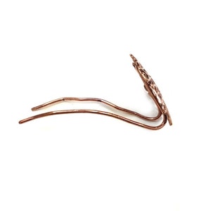 Pu&ograve; includere: Un fermaglio per capelli in oro rosa con un design delicato e intricato. Il fermaglio &egrave; in metallo e ha un gambo lungo e sottile.