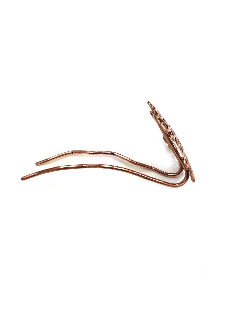 Pu&ograve; includere: Un fermaglio per capelli in oro rosa con un design delicato e intricato. Il fermaglio &egrave; in metallo e ha un gambo lungo e sottile.