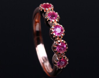 Puede incluir: Un anillo de banda de oro rosa con cinco piedras preciosas rosadas engastadas en un diseño decorativo.