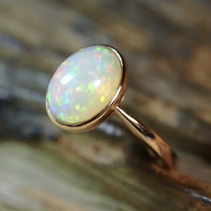 May include: A ring with a white opal gemstone set in a rose gold band.