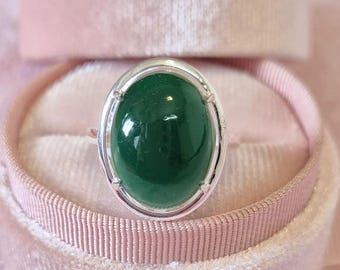 May include: A silver ring with a large oval green gemstone.