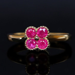 Könnte beinhalten: Ein goldener Ring mit einem Kleeblatt-Design, besetzt mit vier rosafarbenen Rubinen.