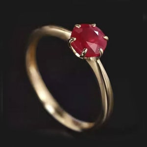 以下が含まれることがあります： 爪留めでセットされた赤いルビーの宝石が付いた金の指輪