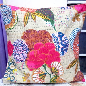 May include: A cream-colored pillow cover with a floral pattern. The pattern features pink, blue, green, and orange flowers and leaves. The pillow cover is quilted and has a subtle sheen.