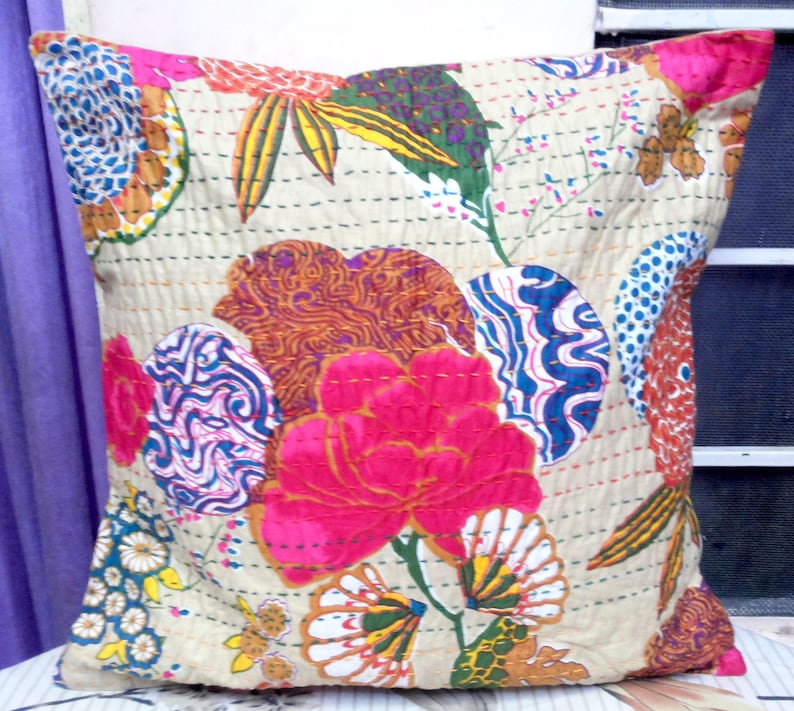 May include: A cream-colored pillow cover with a floral pattern. The pattern features pink, blue, green, and orange flowers and leaves. The pillow cover is quilted and has a subtle sheen.