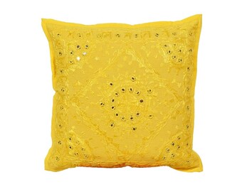 May include: A square yellow decorative pillow with intricate embroidered patterns and small, reflective mirror accents. The pillow has a soft, textured appearance and is designed for home decor. The bright yellow color adds a vibrant touch to any room.